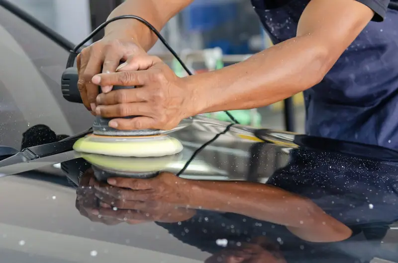 Dual action polisher with a yellow pad on glossy black paint