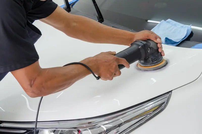 Machine polishing a white hood with a microfiber towel on the cowl