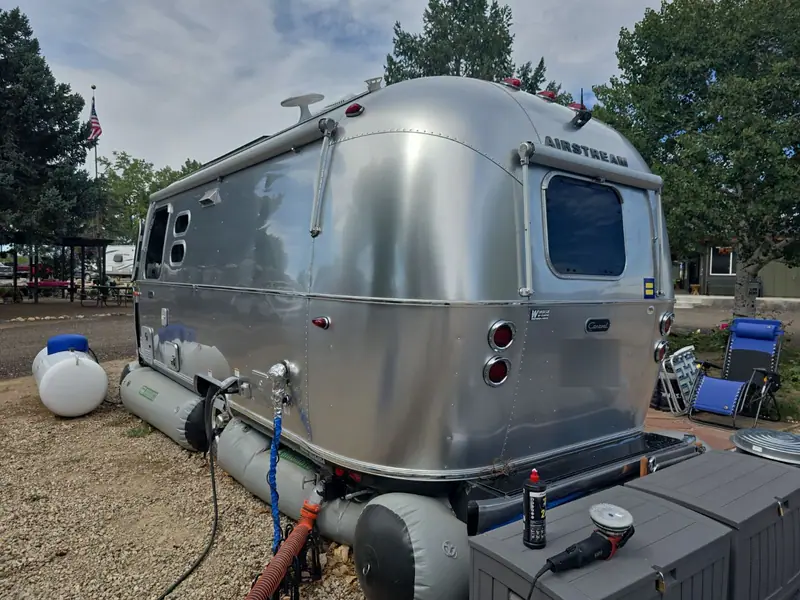 Polished aluminum Airstream travel trailer with a polisher set up beside it
