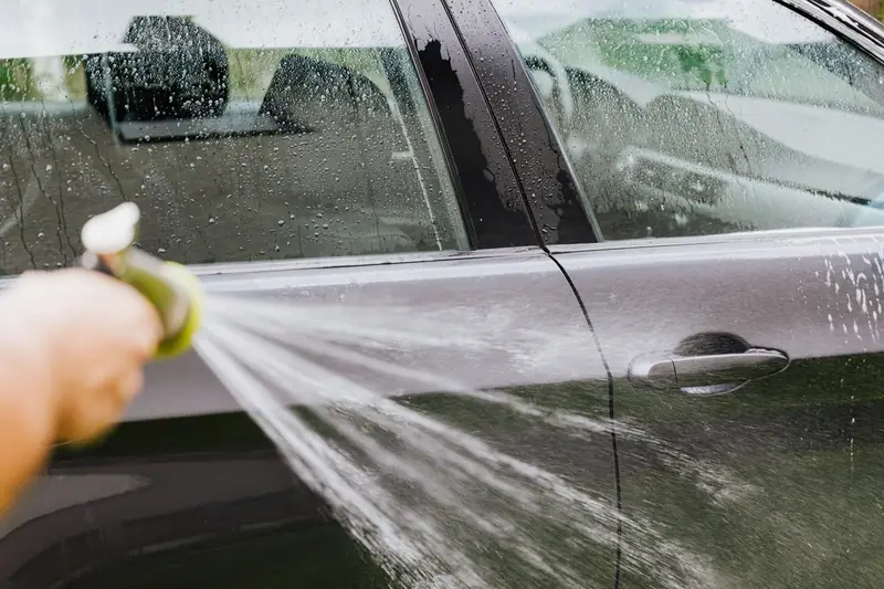 Rinsing a car door with a hose