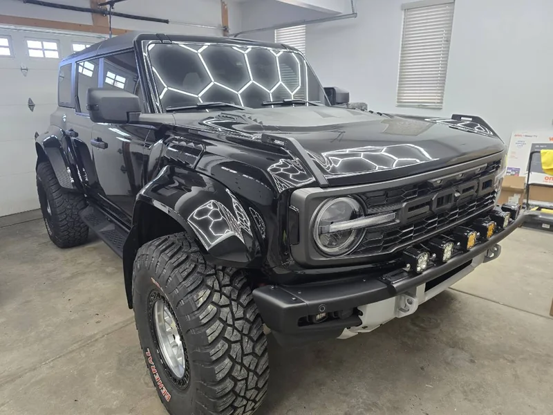 Black Ford Bronco with hexagon garage lights reflecting off the hood and fenders