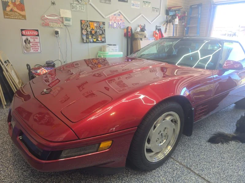 Red Chevrolet Corvette C4 in a home garage under hexagon lights