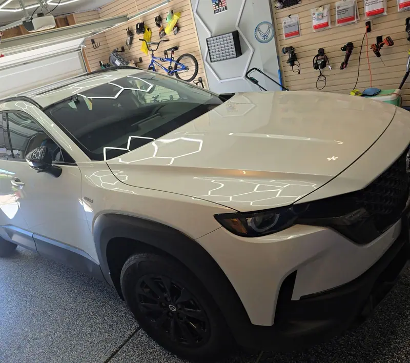 White Mazda SUV detailed in the garage under hexagon lights