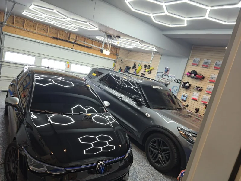 Black VW Golf R hood reflecting hexagon lights in a garage