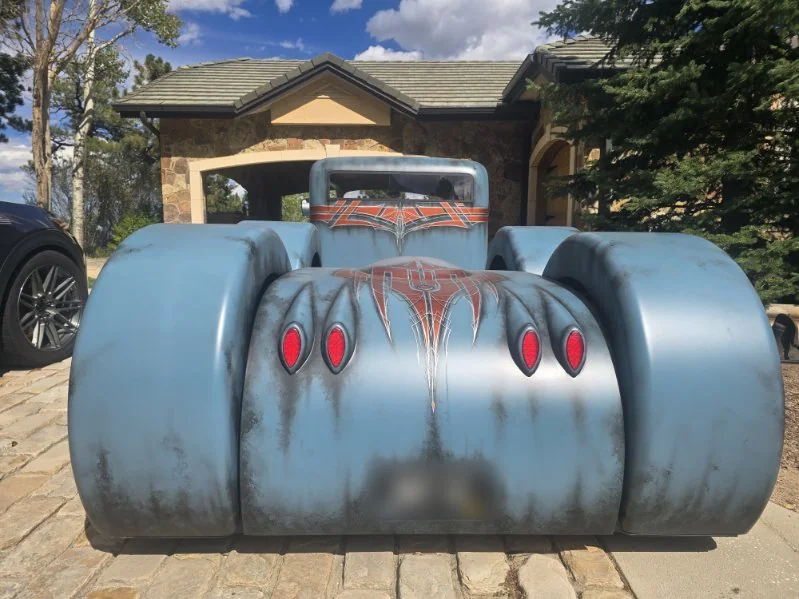Rear of a blue patina rat rod with orange pinstriping and red tail lights